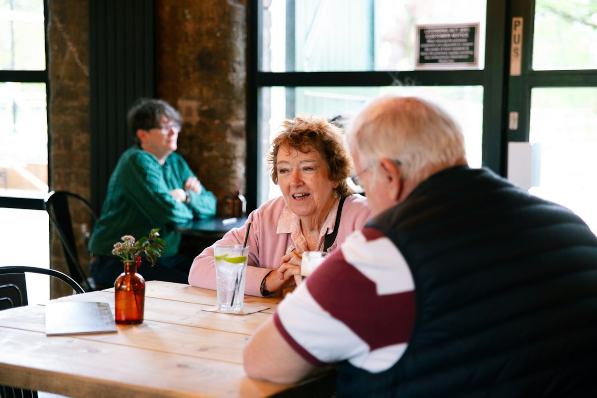 Two older couples chatting over drinks at a cafe table